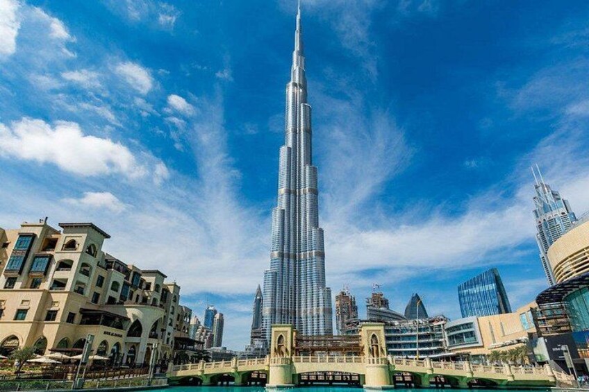 Burj Khalifa, en hög skyskrapa, omgiven av andra byggnader och en klar, blå himmel. 1