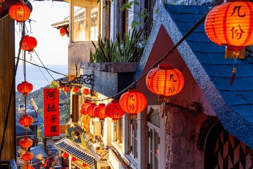 A street with red lanterns, traditional architecture, and a sign with Chinese characters. 2