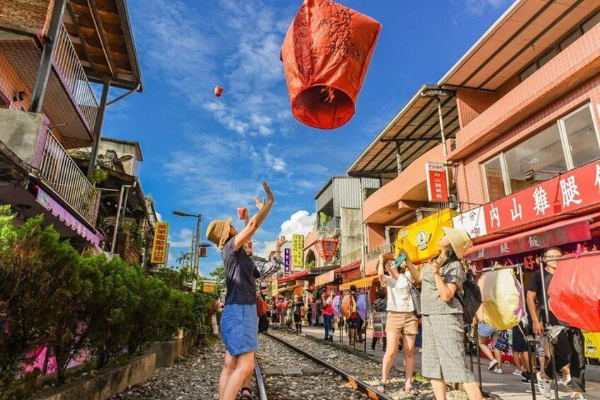 A street with people releasing red lanterns into the sky. 1