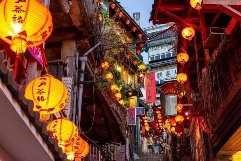A narrow street lined with traditional buildings, adorned with hanging lanterns and banners. 5