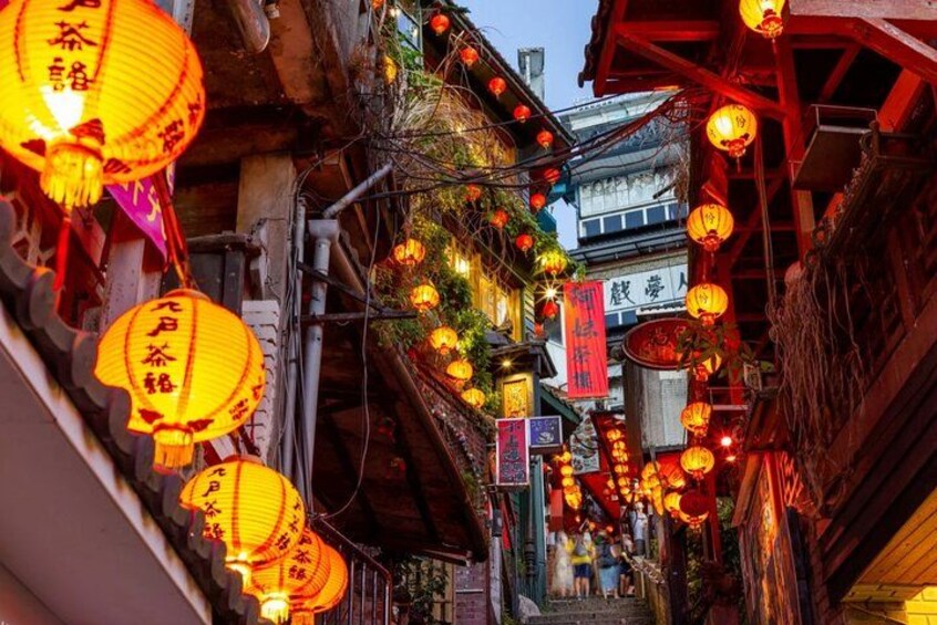 A narrow street lined with traditional buildings, adorned with hanging lanterns and banners. 3