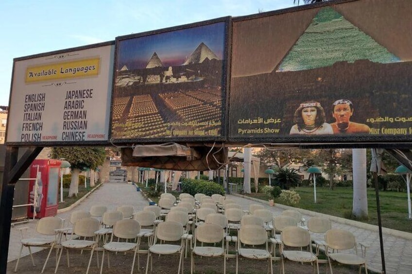 A row of empty chairs and a signboard with language options and a pyramid display. 1