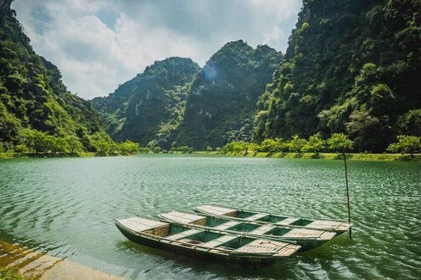 A rowboat floating on a calm river surrounded by lush green mountains. 4