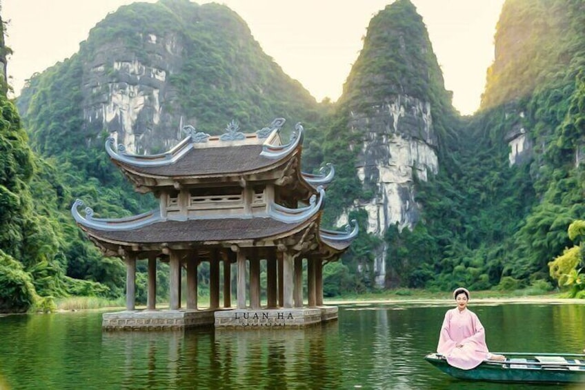 A traditional pavilion on a lake with a person in pink attire. 1