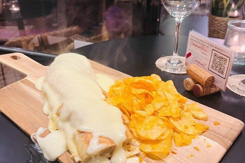 A wooden board with a rolled omelette covered in cheese and potato chips. 2