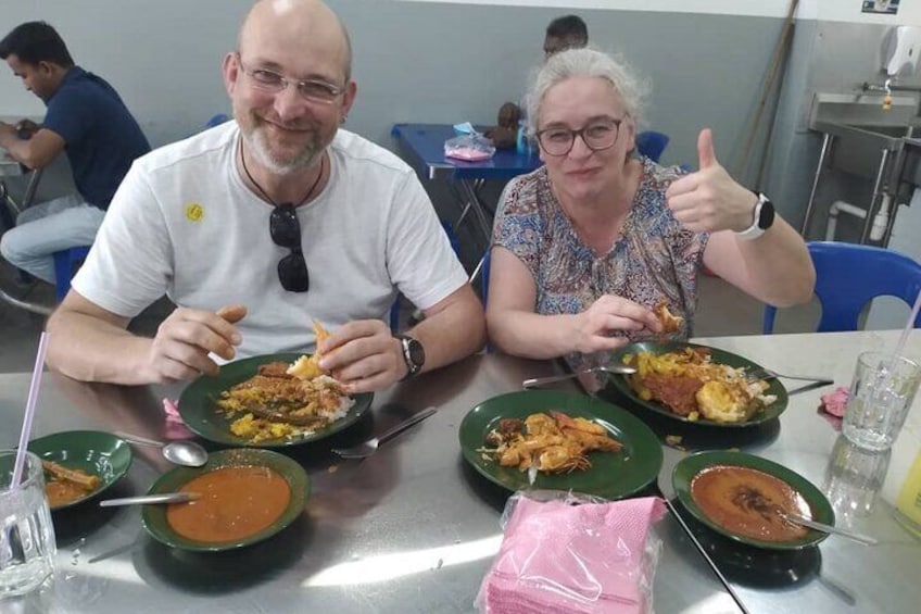 Two people sitting at a table with plates of food, including bowls of soup and a plate with a piece of meat. 3
