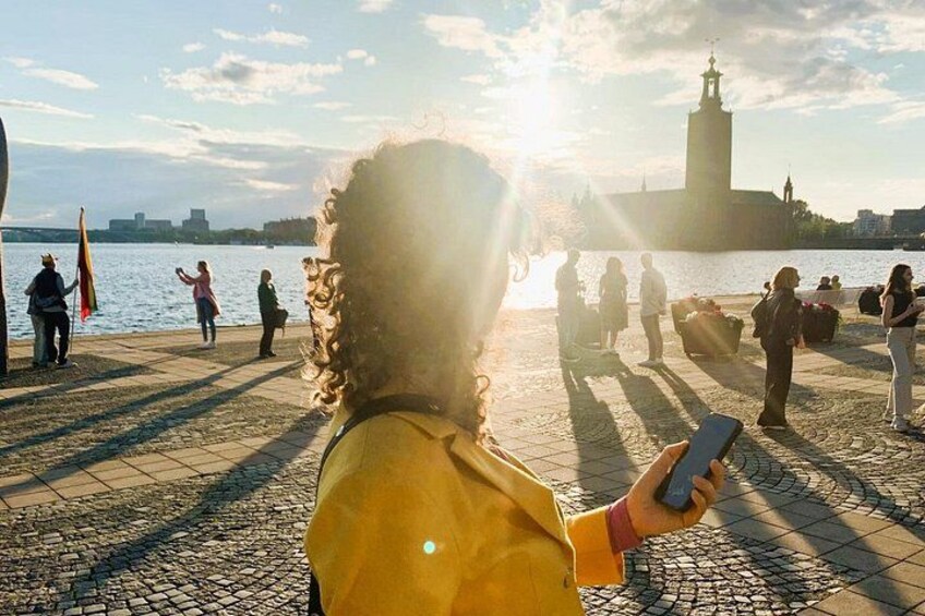 A person taking a photo with a smartphone, a body of water, a tower, and a paved walkway. 2