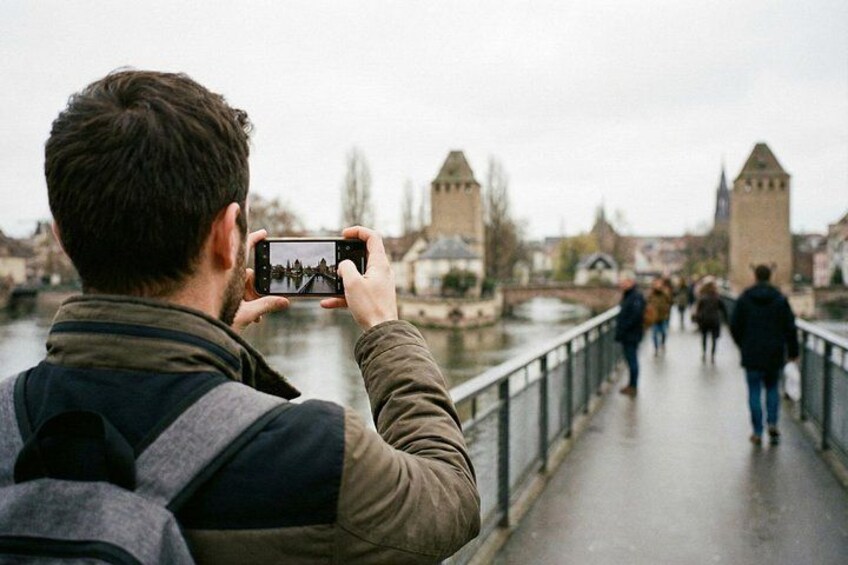 Une personne prend une photo d’un pont avec des tours, une rivière et des bâtiments en arrière-plan. 5