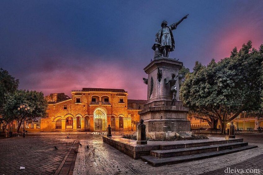 A historic building with a statue in front, under a twilight sky. 1