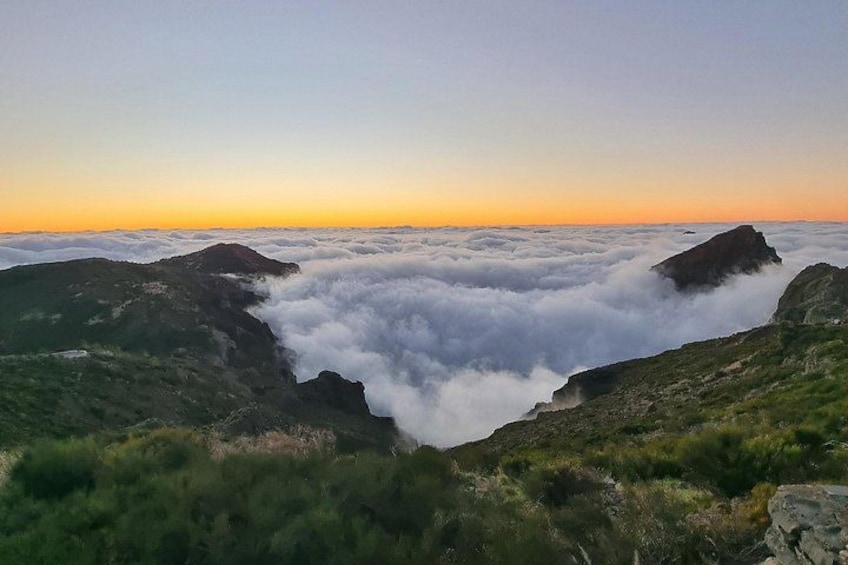 A mountainous landscape with a valley filled with clouds, surrounded by green hills. 3