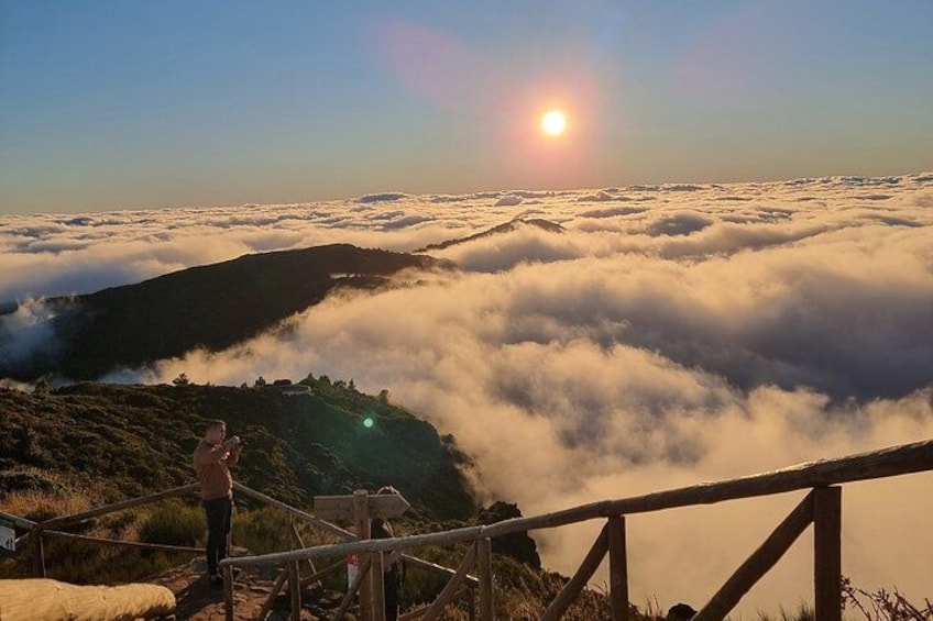 A sunrise over a mountainous landscape with a person standing on a wooden staircase. 2