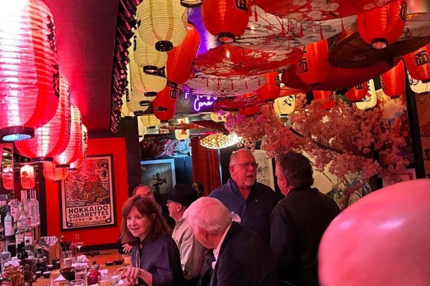 A crowded bar with red lanterns and a poster of Hokkaido. 2
