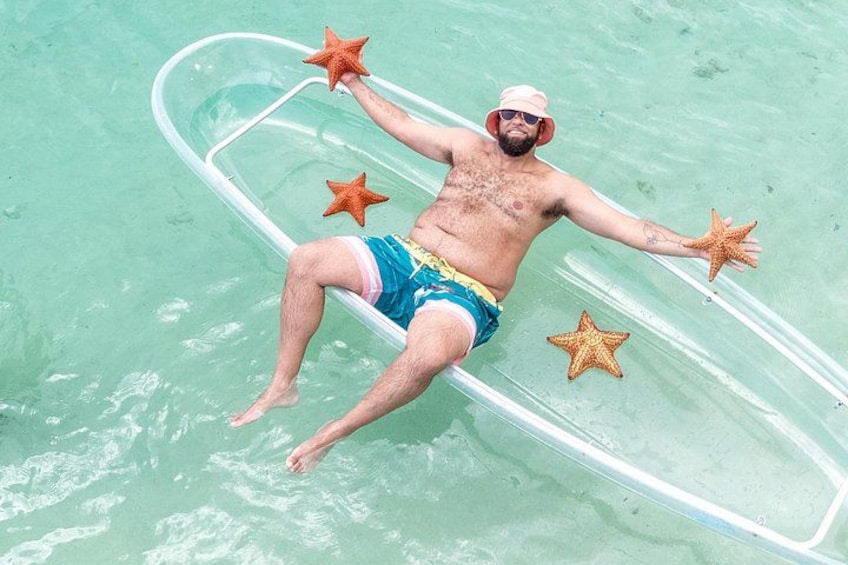 A person floating on a raft in clear water with starfish. 5
