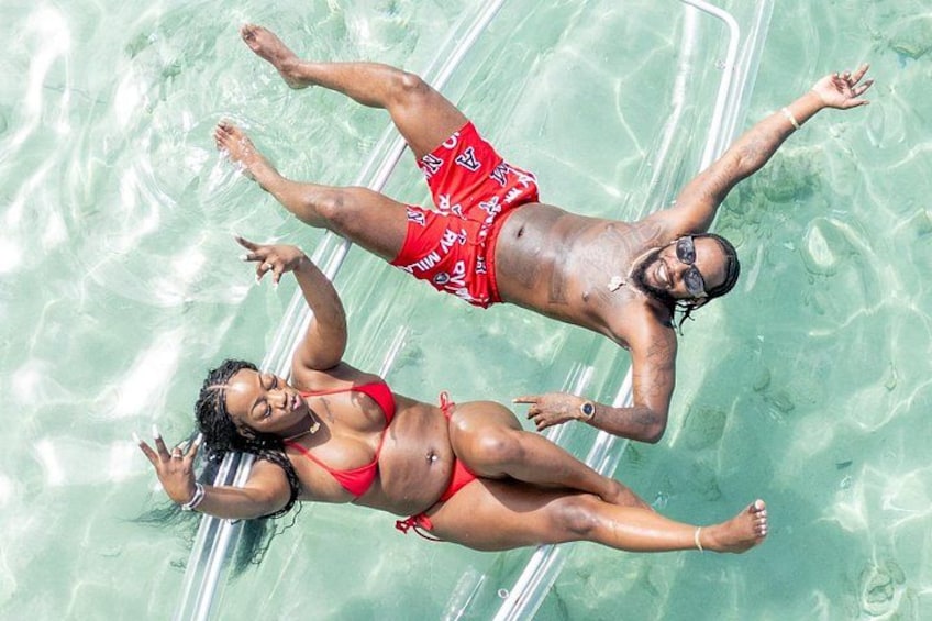 Two people floating on a clear blue water surface. 4