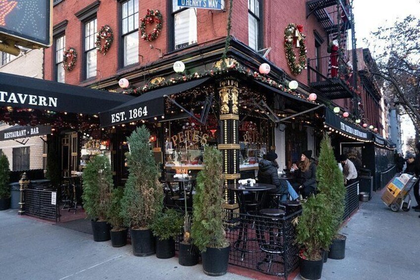 A tavern with outdoor seating, Christmas decorations, and a sign indicating it was established in 1864. 3