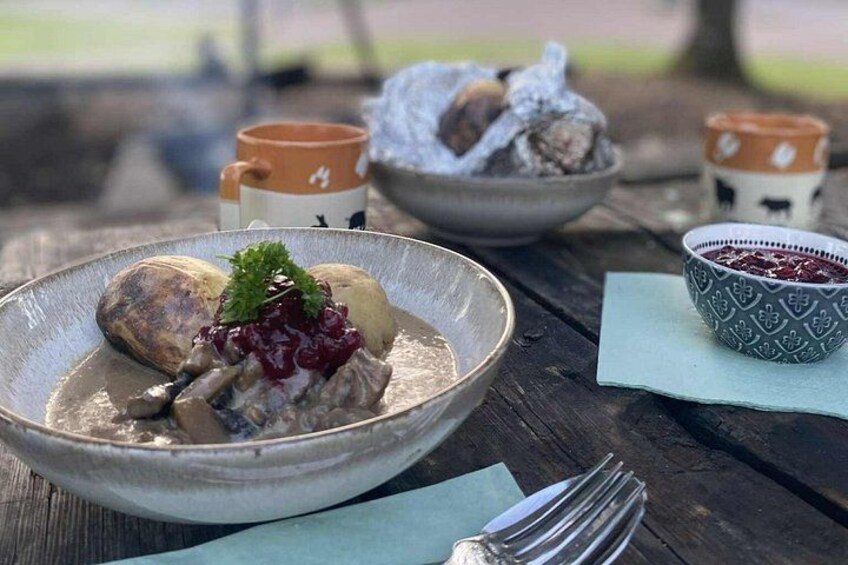 A rustic outdoor dining setting with a bowl of food, a cup, and a bowl of berries on a wooden table. 2