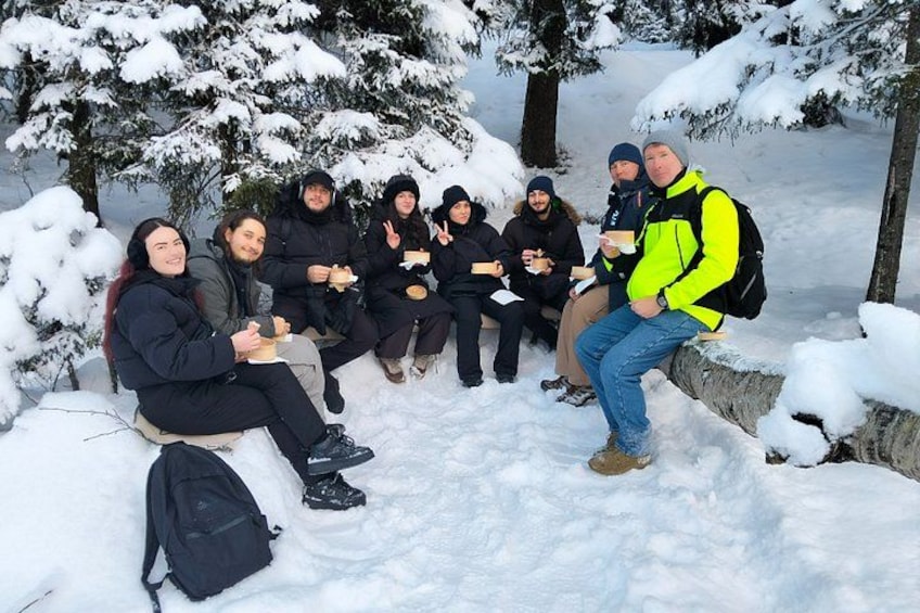 A group of people sitting on a snow-covered rock in a snowy forest. 5