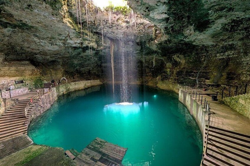 A turquoise pool with a waterfall, surrounded by stone walls and wooden walkways. 4