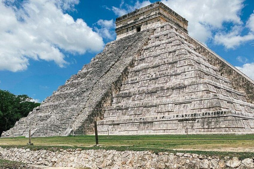 A large pyramid structure with a flat top, surrounded by a grassy area and a stone wall. 2