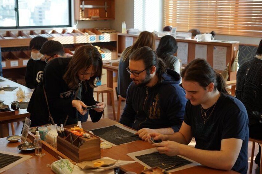 People sitting at tables, working on electronic devices. 4