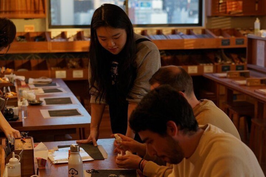 A group of people engaged in a craft activity at a wooden table with various tools and materials. 3
