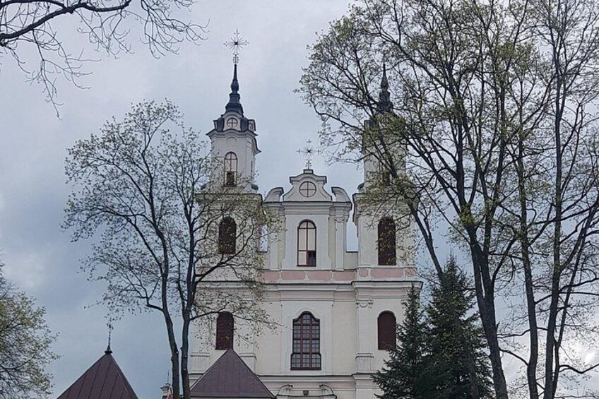 A church with two towers and a steeple, surrounded by leafless trees. 2