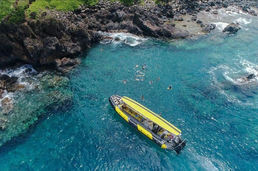 A yellow boat in clear blue waters surrounded by rocky cliffs. 1