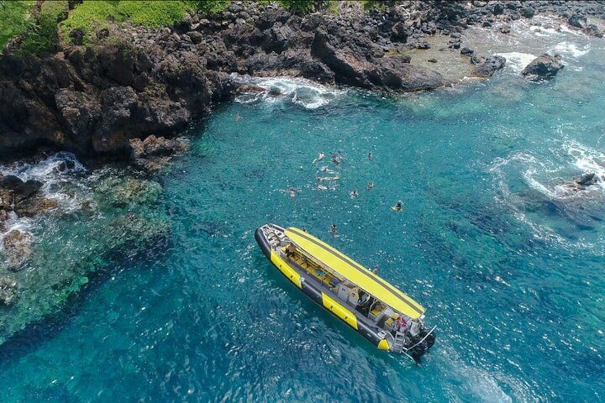 A yellow boat with people on a rocky coastline and clear blue water. 1