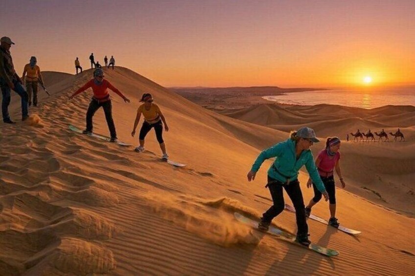 Menschen snowboarden bei Sonnenuntergang auf Sanddünen. 5