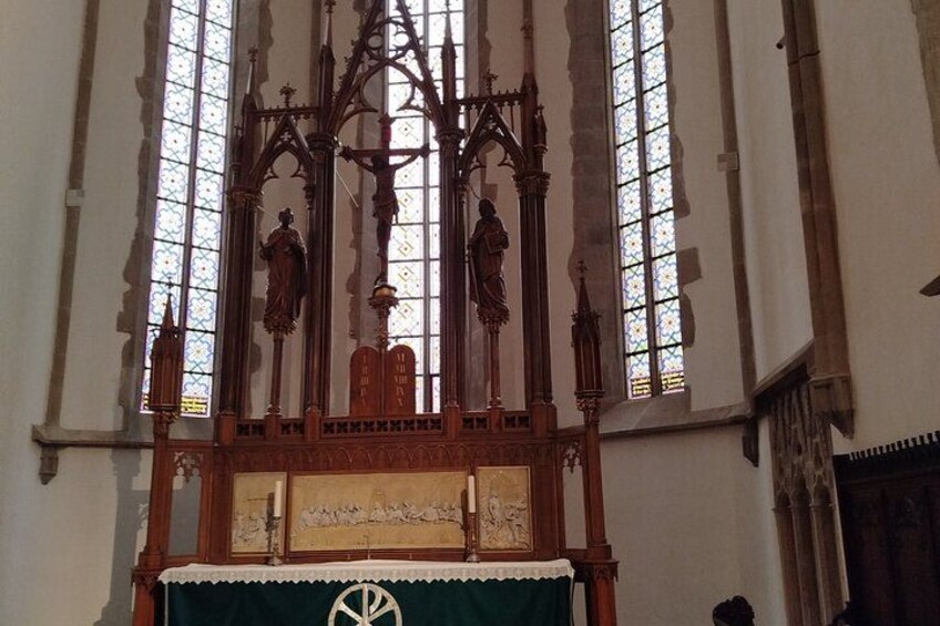 A church interior with stained glass windows, wooden altars, and religious statues. 2