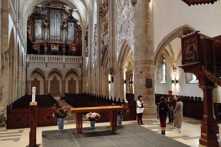 A church interior with an organ, pews, and a group of people. 3