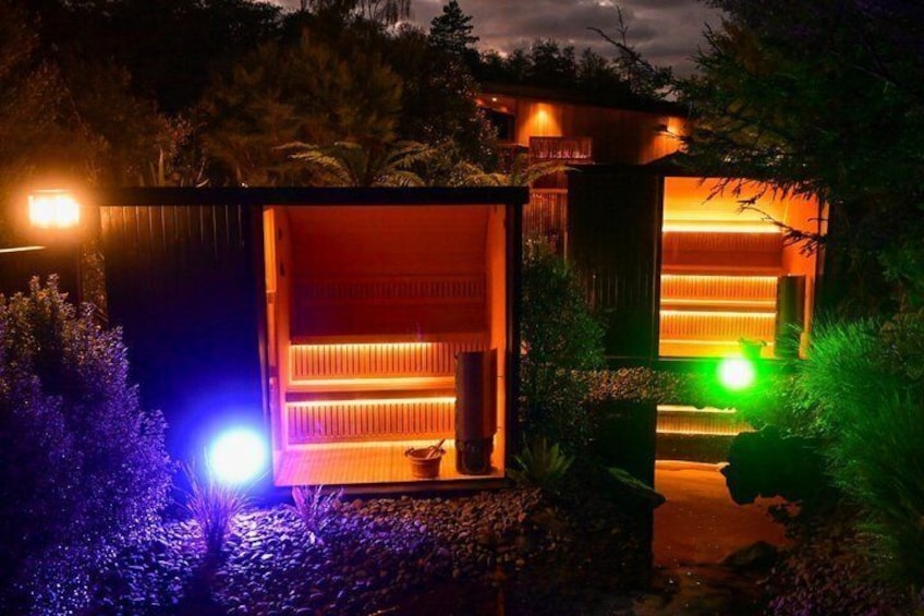 A wooden structure with warm interior lighting, surrounded by vegetation. 3