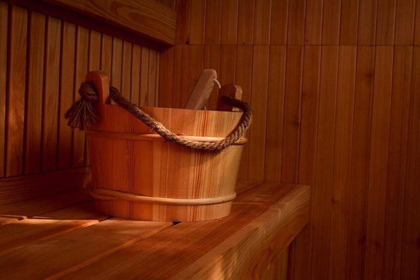 Un seau en bois avec une anse en corde, posé sur un banc en bois dans un sauna. 2
