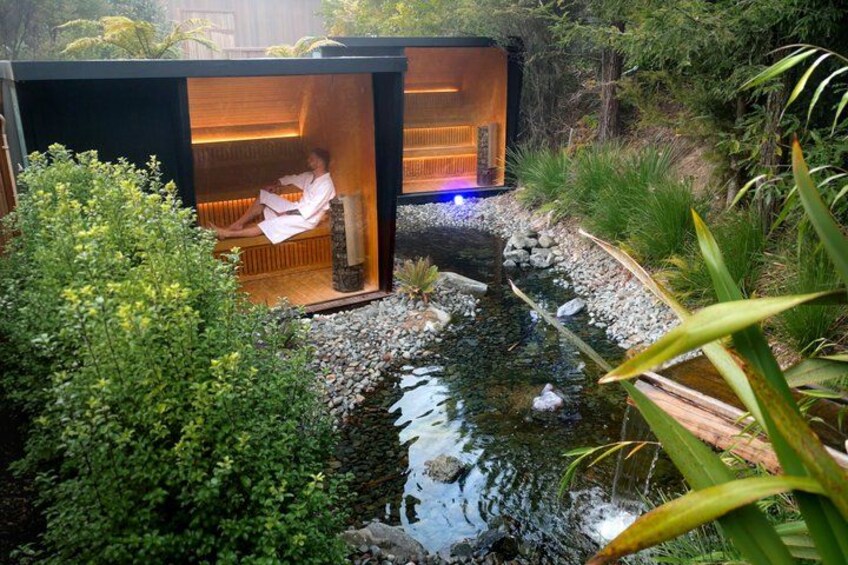 Un spa extérieur moderne doté d’une structure en bois, d’un petit étang et d’une végétation luxuriante. 1