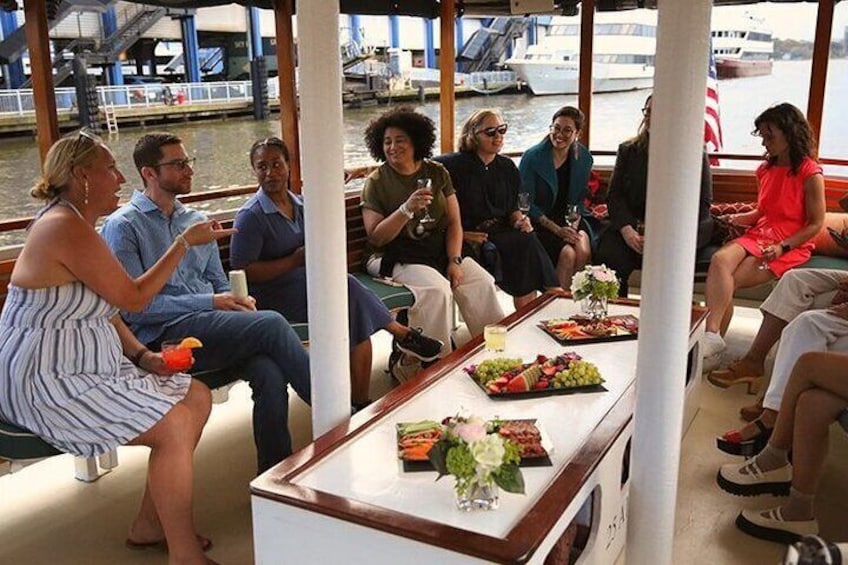 Een groep mensen op een boot met eten en drinken op tafel. 4