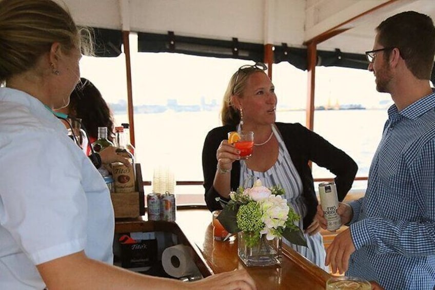 Een groep mensen op een boot met een bar, flessen en een bloevas. 3