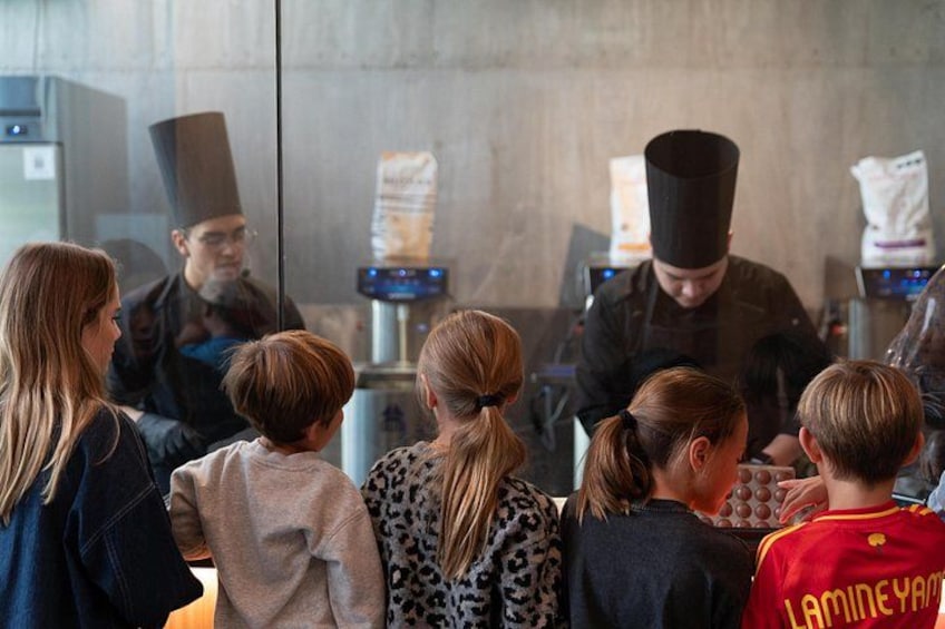 Un grupo de personas, entre ellas niños, observando a cocineros en una cocina. 5