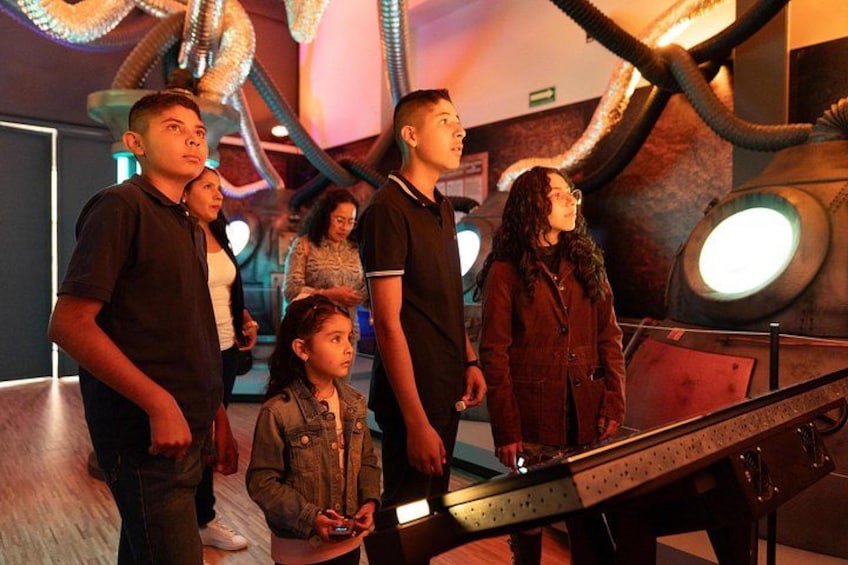 Un grupo de personas observando una exhibición temática del espacio, con una gran estructura iluminada al fondo. 1