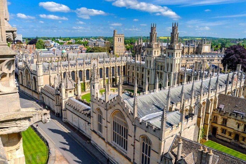 A historic university campus with Gothic architecture, including a prominent clock tower and a large central building with arched windows. 2