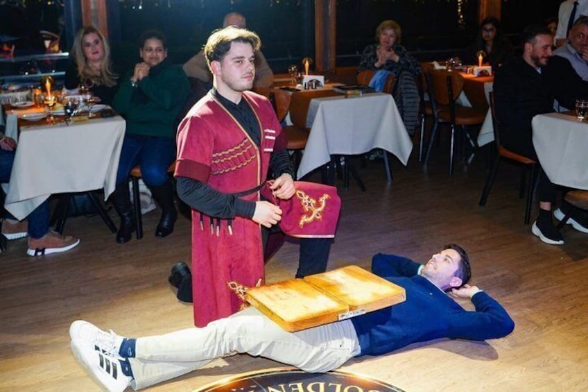 A person in a red robe holding a book, standing over another person lying on the floor. 4