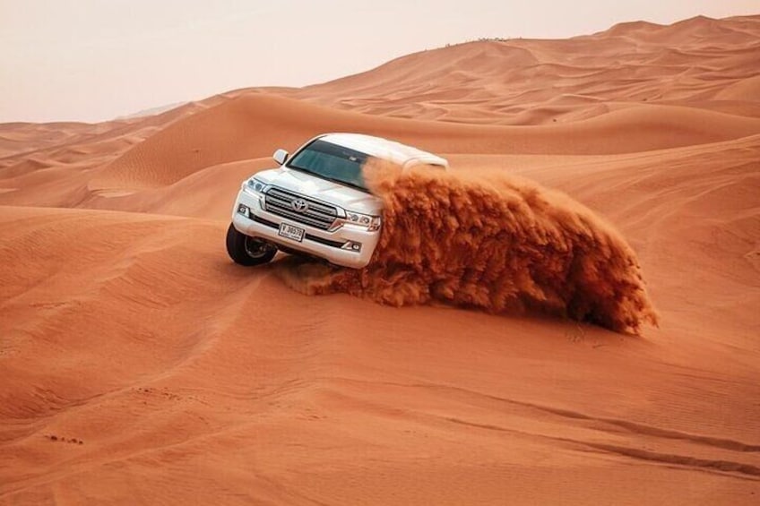 A white SUV driving through a desert with sand dunes. 1
