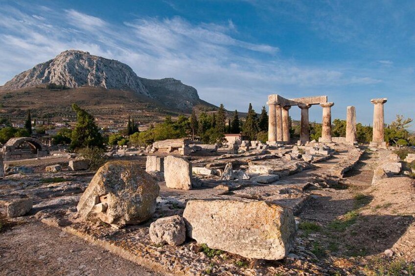 Ruinas antiguas con columnas, una montaña al fondo y rocas dispersas. 1