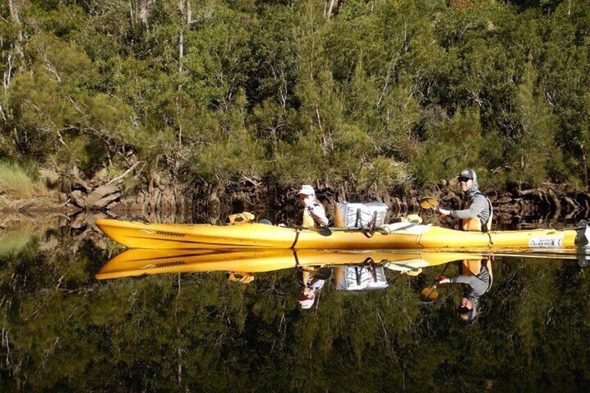 A yellow canoe on calm water with two people paddling. 3
