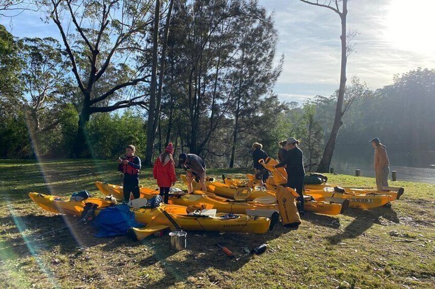 People preparing kayaks by a lake surrounded by trees. 5