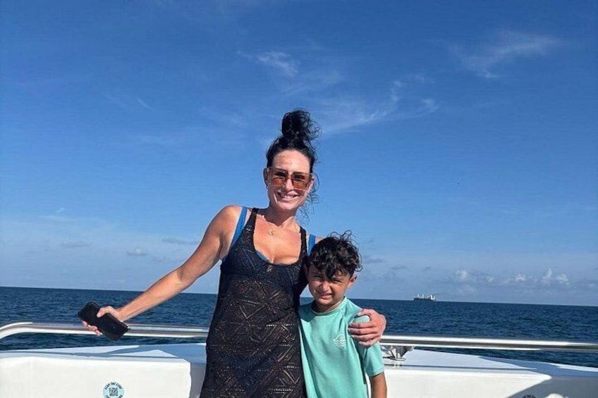 A person on a boat with a child, water in the background, and a distant ship. 3