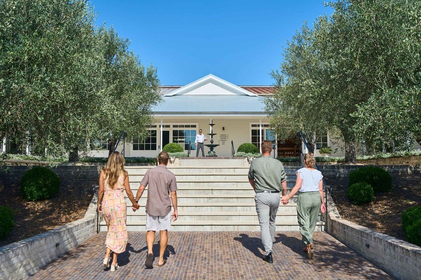 A building with a covered entrance, steps leading up to it, and two trees on either side. 4