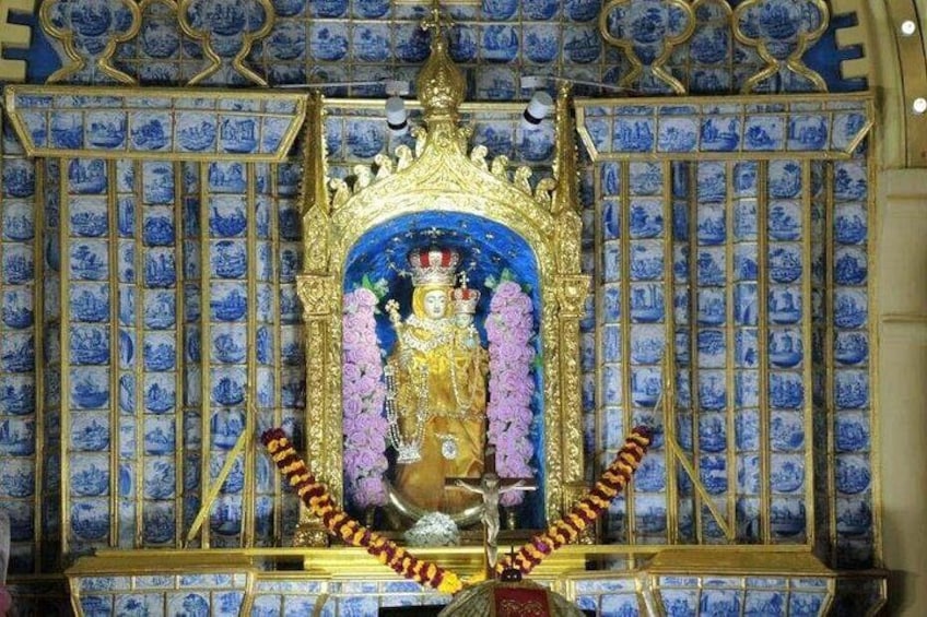 Una estatua en un templo con paredes de diseño azul y un marco dorado. 2