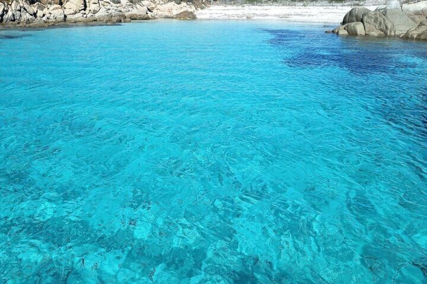 Une piscine d’un bleu turquoise éclatant, bordée de rochers blancs et d’une plage de sable. 3
