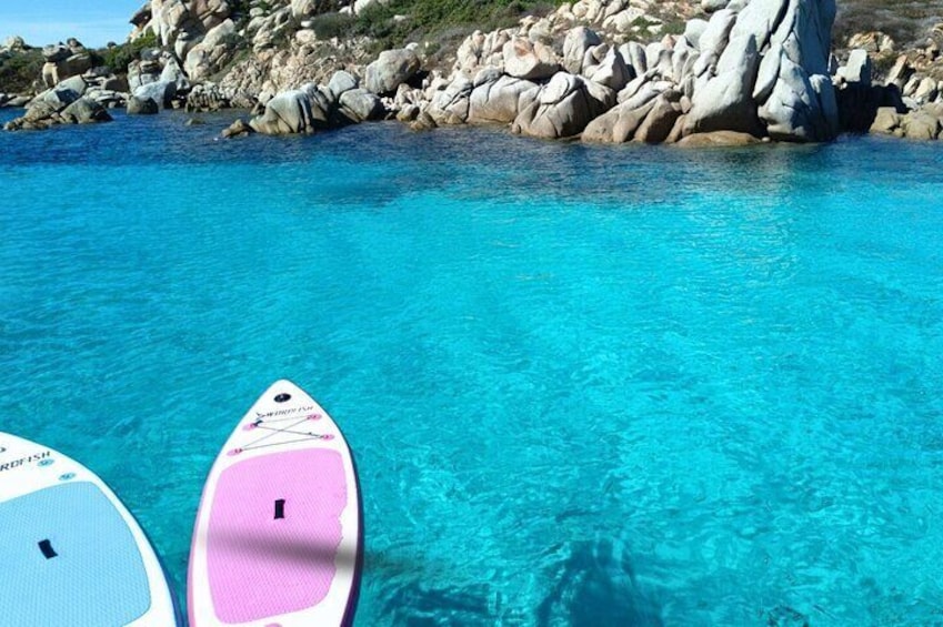 Deux planches de surf sur une eau turquoise et limpide, avec des falaises rocheuses en arrière-plan. 4