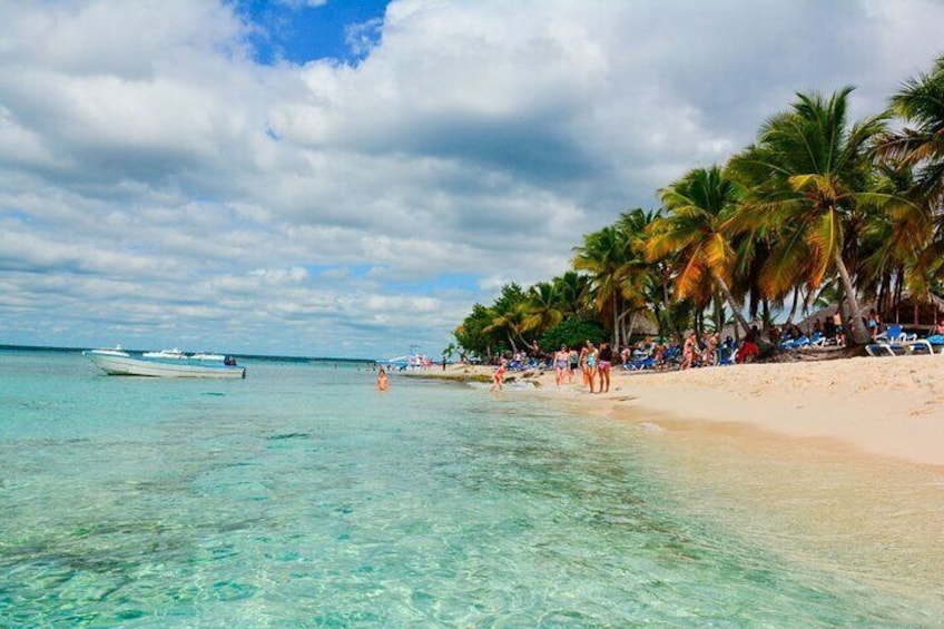 Ein Strand mit klarem türkisblauem Wasser, Palmen und einem Boot in der Ferne. 1